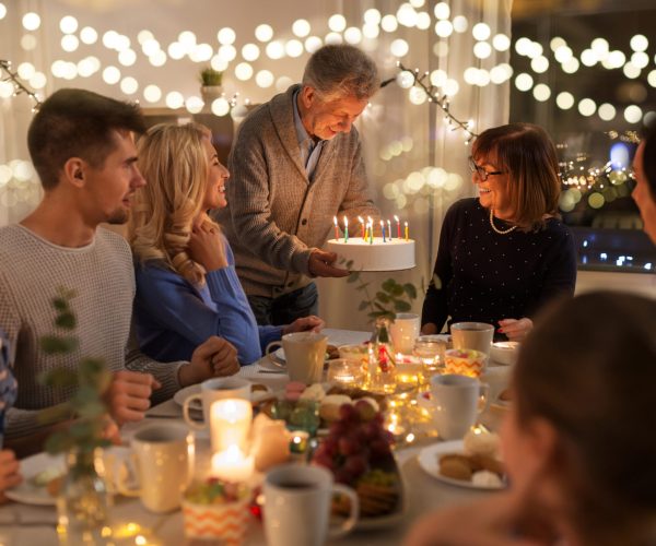 dinner party and celebration concept - happy family with cake celebrating grandmothers birthday at home